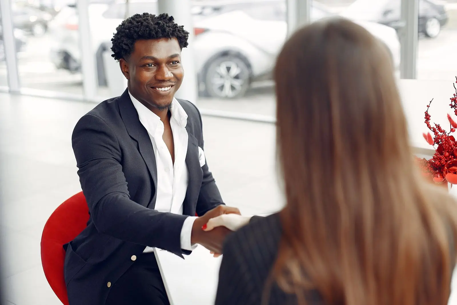 Un chargé d'affaires souriant serre la main d'une cliente dans une agence bancaire lumineuse