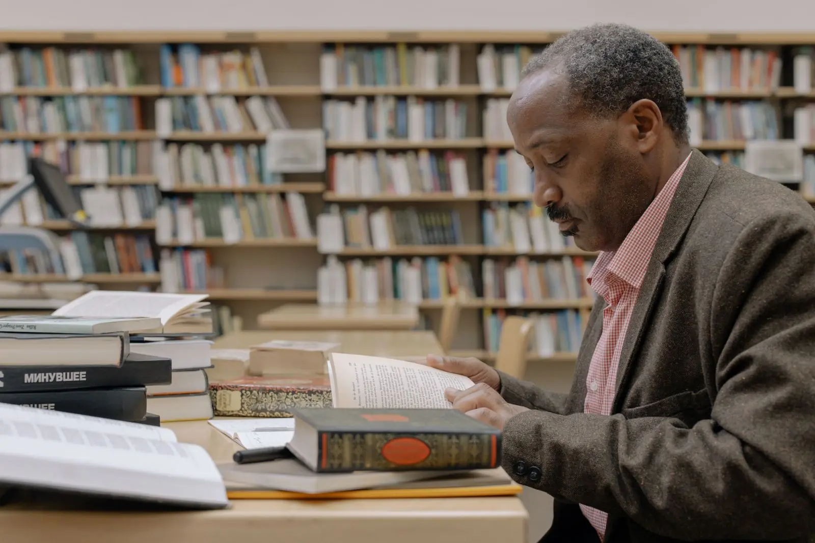 Un homme consulte des ouvrages et des documents dans une bibliothèque